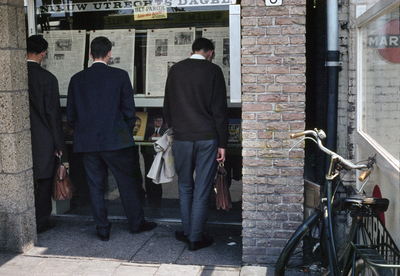 849837 Afbeelding van enkele personen die de krant lezen in de vitrines van het kantoor van het Nieuw Utrechts Dagblad ...